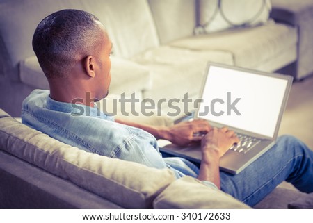 Over shoulder view of casual man using laptop in living room