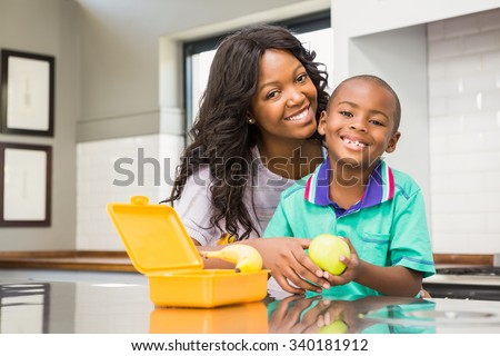 Smiling mother preparing sons school lunch in the kitchen