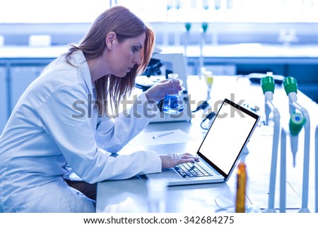 Scientist looking at beaker of chemical at the university