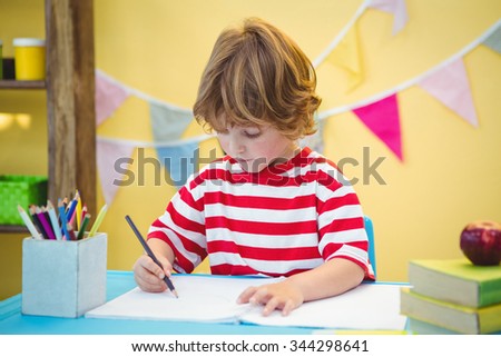 Boy using a pencil to write on paper at the desk