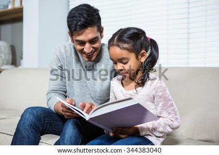 Happy father and daughter using laptop on the sofa in living room