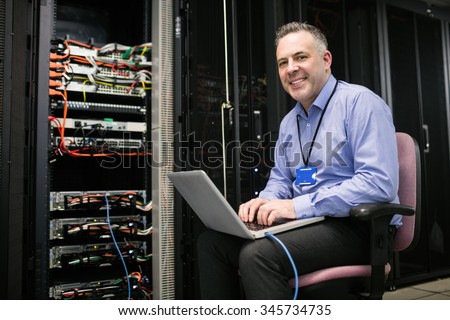 Technician using laptop in server room at the data centre