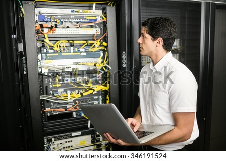 Technician using laptop to analyse server at the data centre