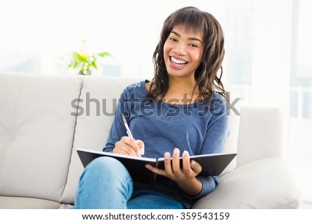 Smiling casual woman writing notes at home