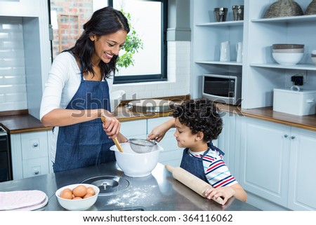 Smiling mother cooking with her son in kitchen at home
