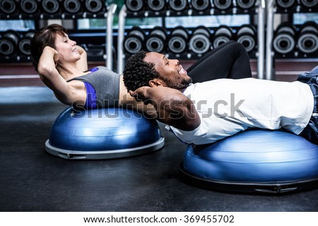 Fit couple doing bosu ball exercises at gym