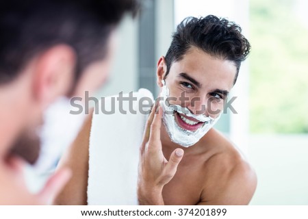Handsome man shaving his beard in bathroom