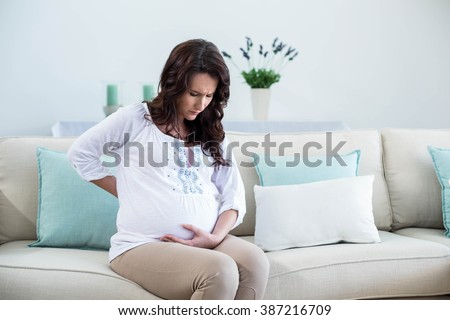 Pregnant woman with painful back in living room