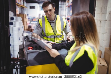 Warehouse worker talking with forklift driver in warehouse