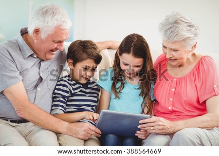 Senior couple and their grand children using digital tablet in living room