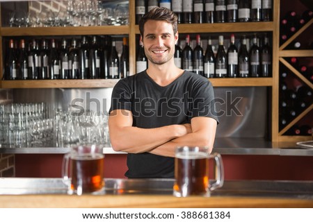 Handsome bar tender standing behind his counter in a pub