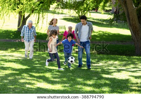Smiling family playing football in the garden