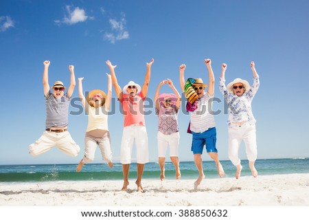Happy senior friends jumping on the beach