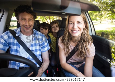 Smiling family sitting in the car and driving