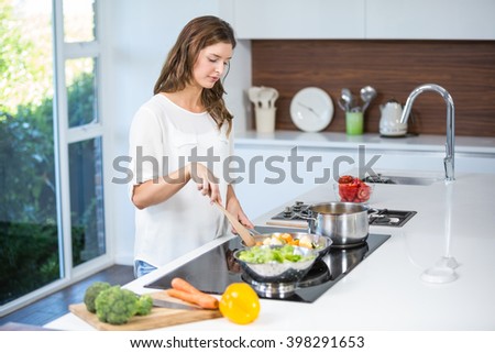 Beautiful young woman cooking food at home
