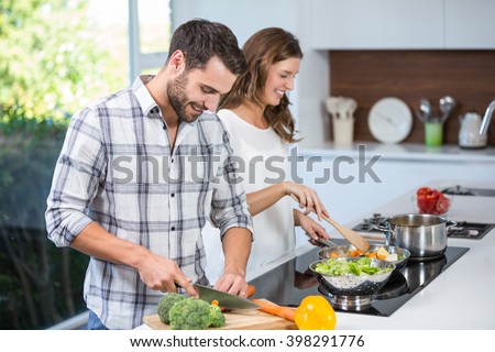 Happy young couple preparing food at kitchen counter