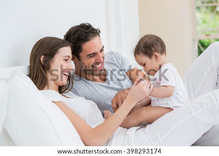 Cheerful couple playing with baby girl on bed at home