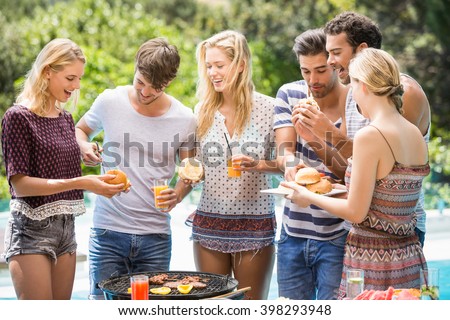 Group of friends having hamburgers and juice at outdoors barbecue party