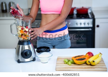 Mid section of a woman preparing fruit smoothie in blender