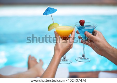 Hands of couple toasting martini glass near pool