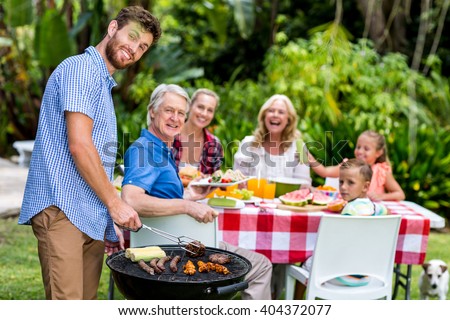 Happy father grilling food on barbeque at yard