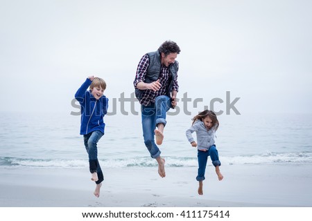 Full length of cheerful family jumping at sea shore against clear sky