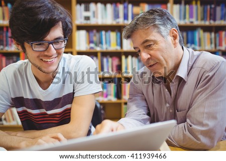 Professor assisting a student with studies in college library