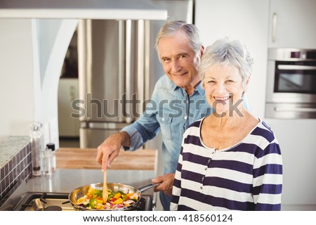 Portrait of senior couple cooking food in kitchen