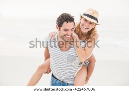Man giving a piggy back to woman on the beach on a sunny day