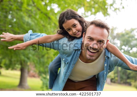 Father giving a piggyback ride to his daughter outdoors