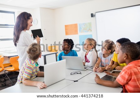A teacher giving lesson with technology in classroom