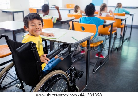 A cute people in wheel chair looking at the camera in classroom