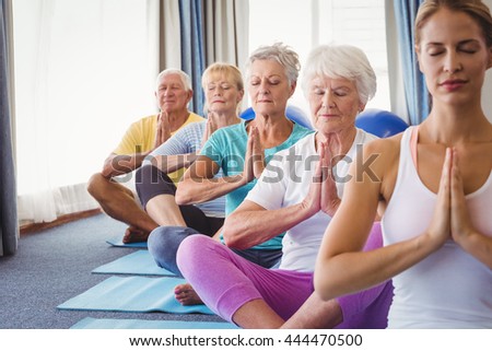Front view of seniors relaxing with fitness instructor in retirement house