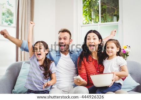 Happy family cheering while watching TV at home