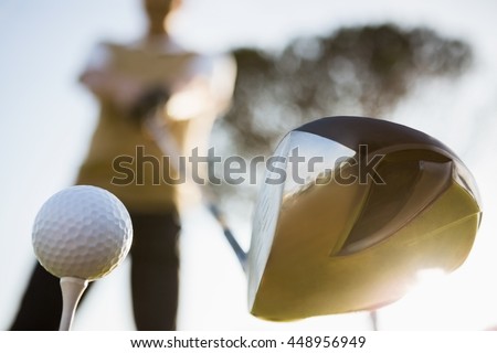 Focus on foreground of golf club and ball on a field