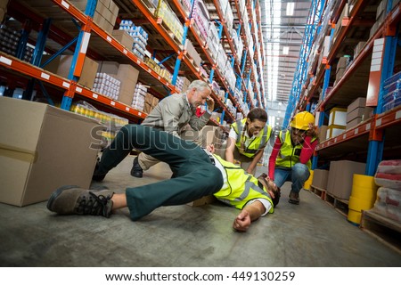 Workers taking care about their colleague lying on the floor in a warehouse