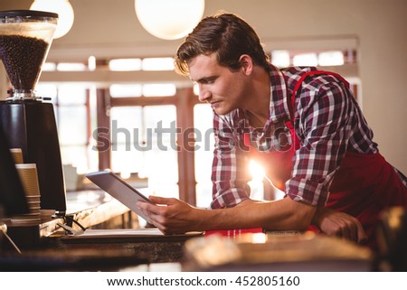 Waiter standing at counter using digital tablet