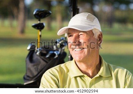 Close-up of smiling golfer man sitting in golf buggy