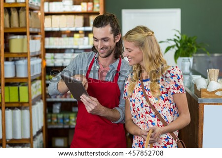Male staff and woman looking at digital tablet in supermarket
