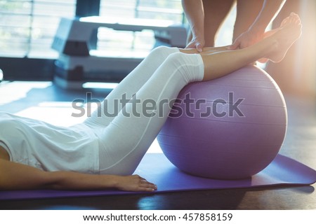 Physiotherapist assisting a patient with exercise ball in clinic