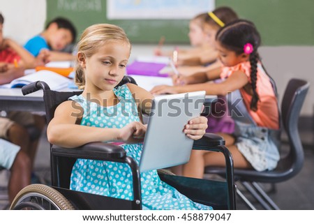Disabled schoolgirl using digital tablet in classroom at school
