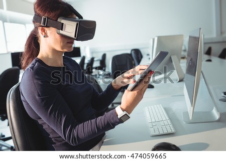 Mature student in virtual reality headset using digital tablet to help with studying at college