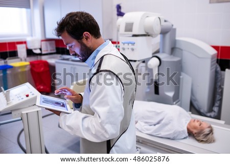Doctor using digital tablet and patient lying on x ray machine in hospital