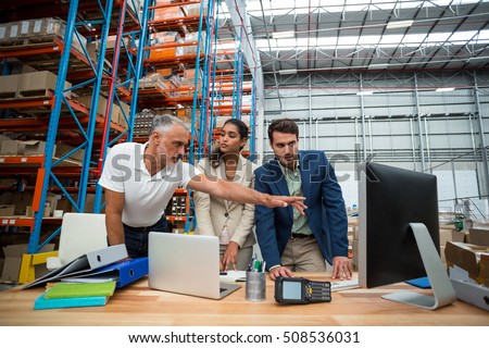 Warehouse managers and worker discussing with computer in warehouse office