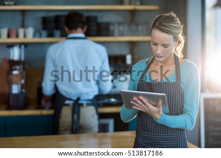 Waitress using digital tablet at counter in cafÃ©