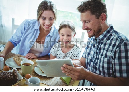 Family using digital tablet while having breakfast at home