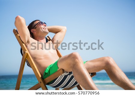 Man sitting and relaxing on deck chair on the beach