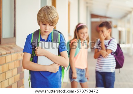 School friends bullying a sad boy in corridor at school