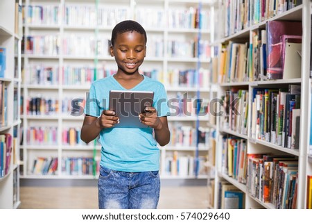 Schoolboy using digital tablet in library at school