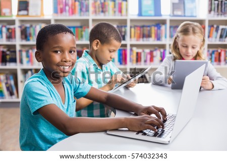 Kids using laptop and digital tablet in library at school